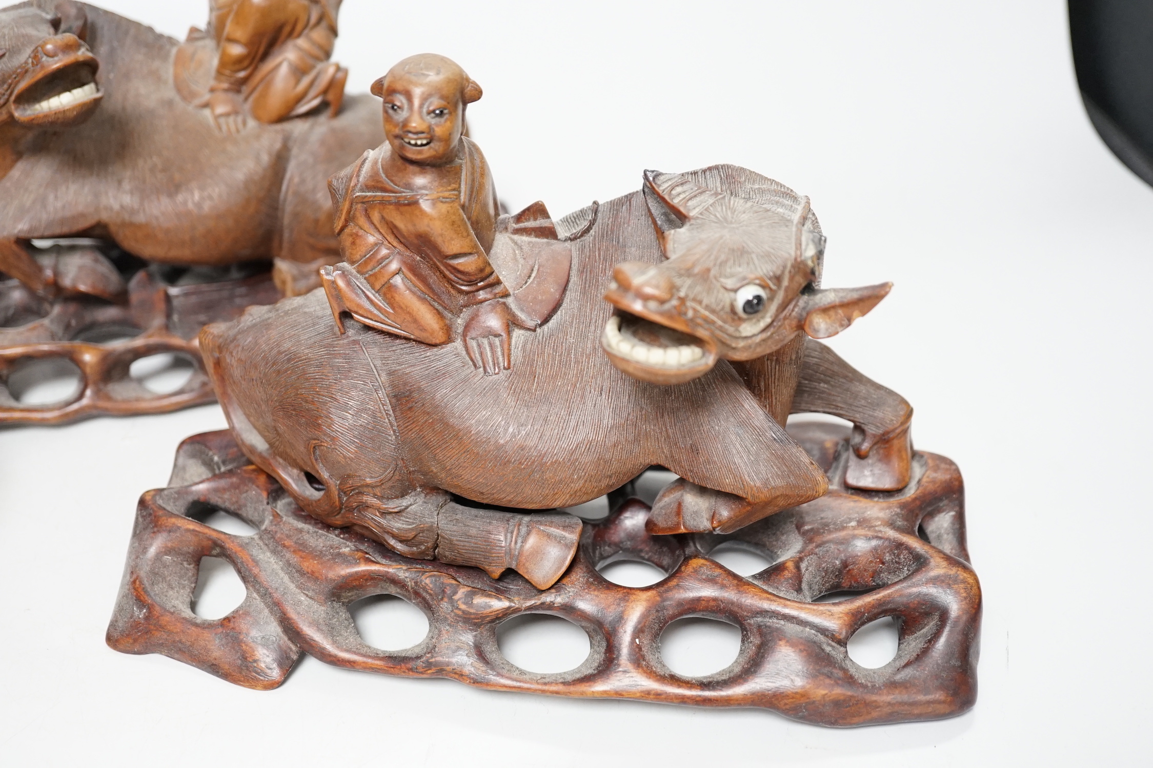 A pair of Chinese carved hardwood buffalo carvings, and a similar figure of a luohan, latter 24cm - damaged